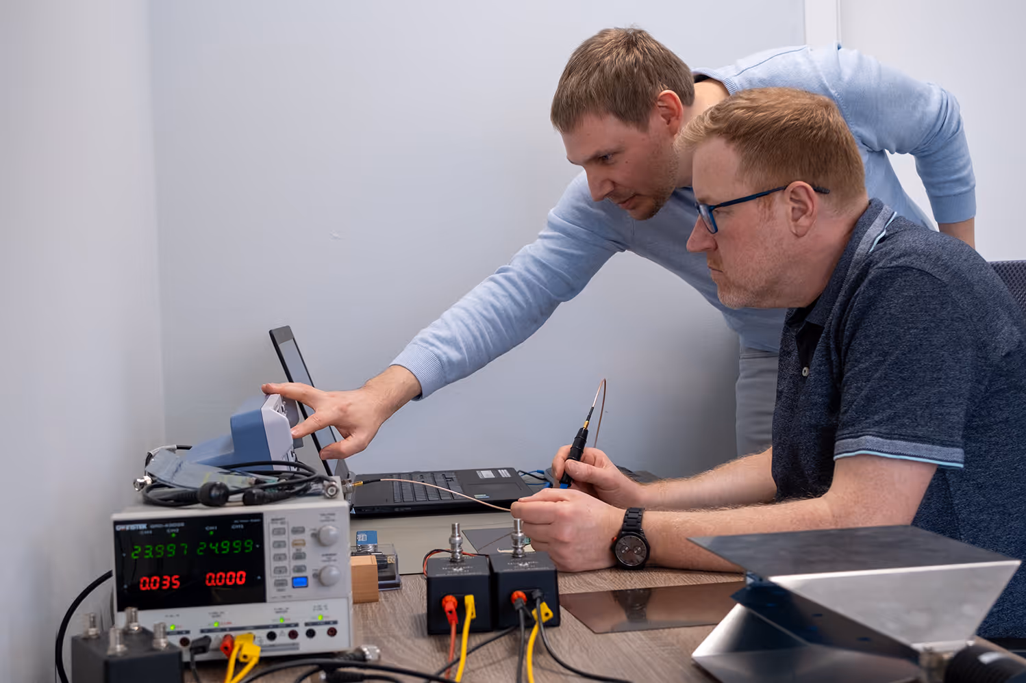 Torsten Krieger steht vor einem Fernseher und erklärt ein elektronisches Bauteil