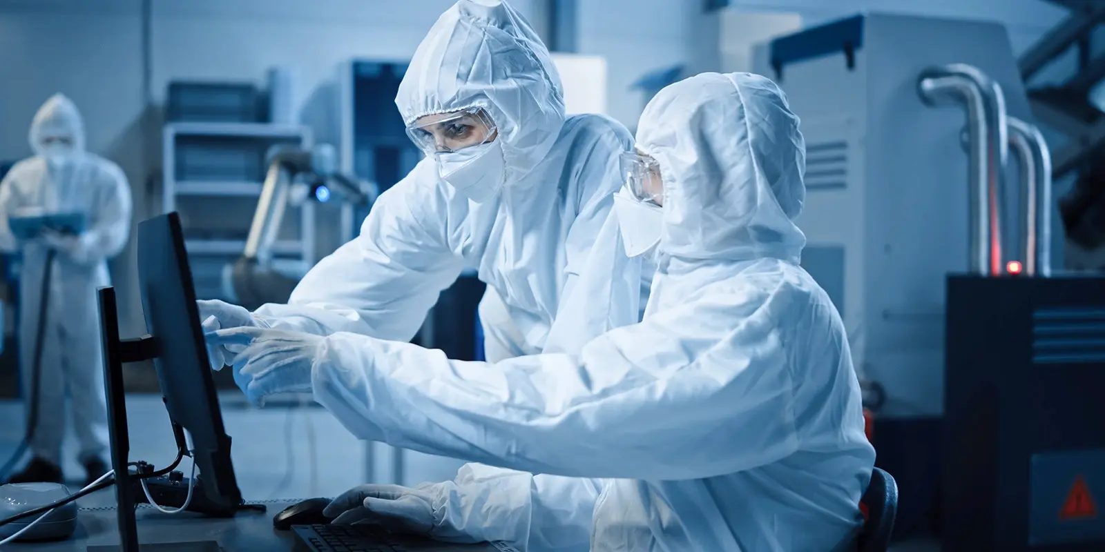 Fabrik-Reinraum: Ingenieur und Wissenschaftler in Schutzanzügen und mit Masken diskutieren, verwenden Computer, die die Steuerung des Infrastruktursystems zeigen. Im Hintergrund CNC-Maschinen, Roboterarm, elektronische Geräte