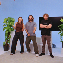 Junge Frau mit hochgestecktem Haar sitzt lächelnd an einem Schreibtisch in einem hellen Raum.