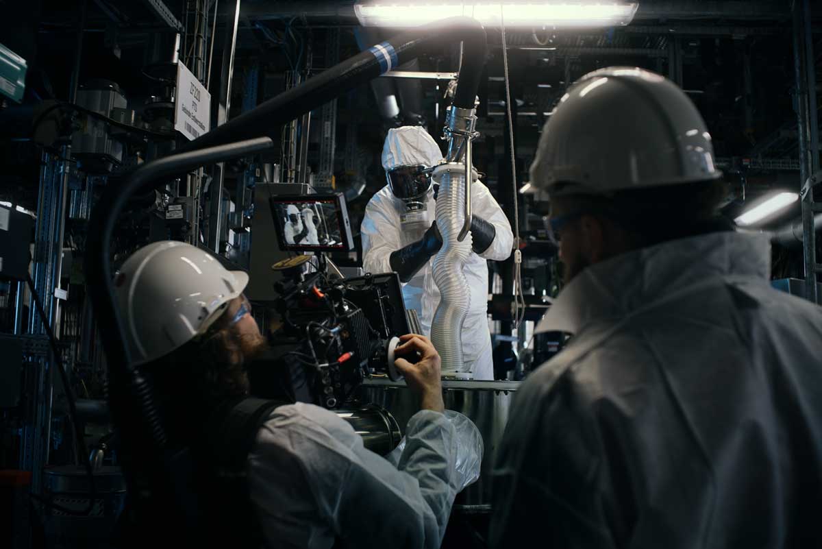 Eine farbenfrohe Cartoon-Illustration von sechs Personen mit verschränkten Armen vor einem modernen Gebäude mit Bayer-Logo, umgeben von Berliner Wahrzeichen wie dem Fernsehturm und dem Brandenburger Tor.