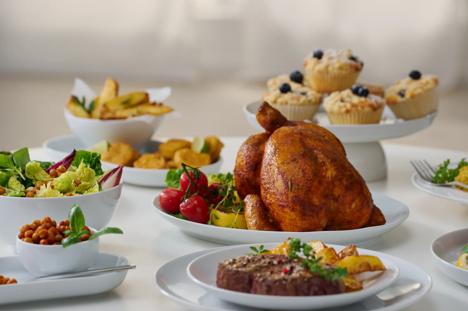 Gedeckte Tafel mit Hähnchen, Muffins, Salat und Pommes aus dem SEVERIN AI-Fryer