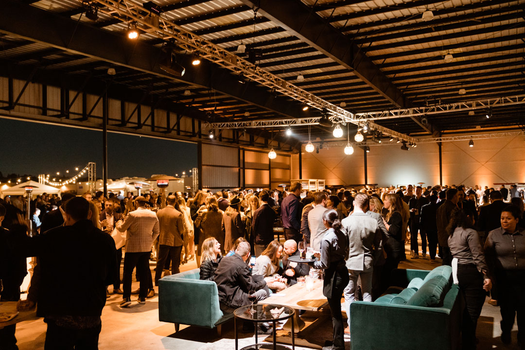 Crowd of guests at the Zendesk corporate party filling The Executive Hangar, green velvet sofas in front