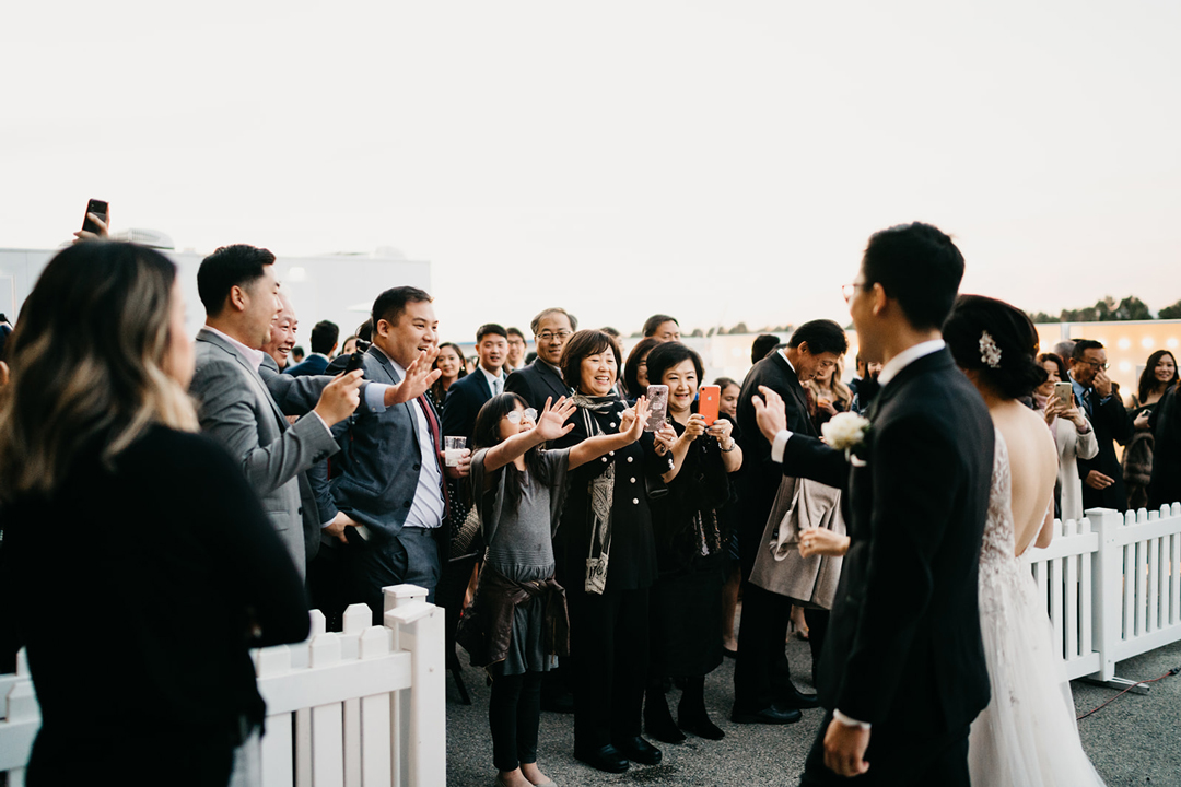 Guests cheering and taking phone photos as Kayla and Justin return from their helicopter ride