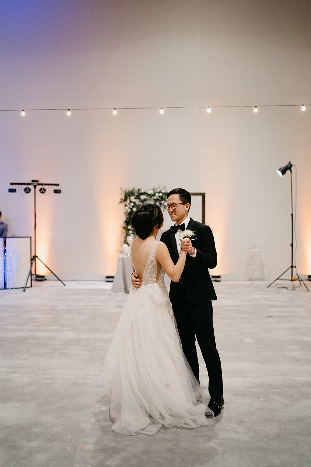 Kayla and Justin sharing their first dance under cafe lights in The Executive Hangar