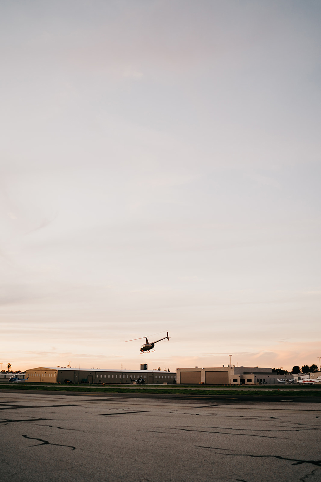 Helicopter carrying the newlyweds flying over the Fullerton Airport hangars at sunset