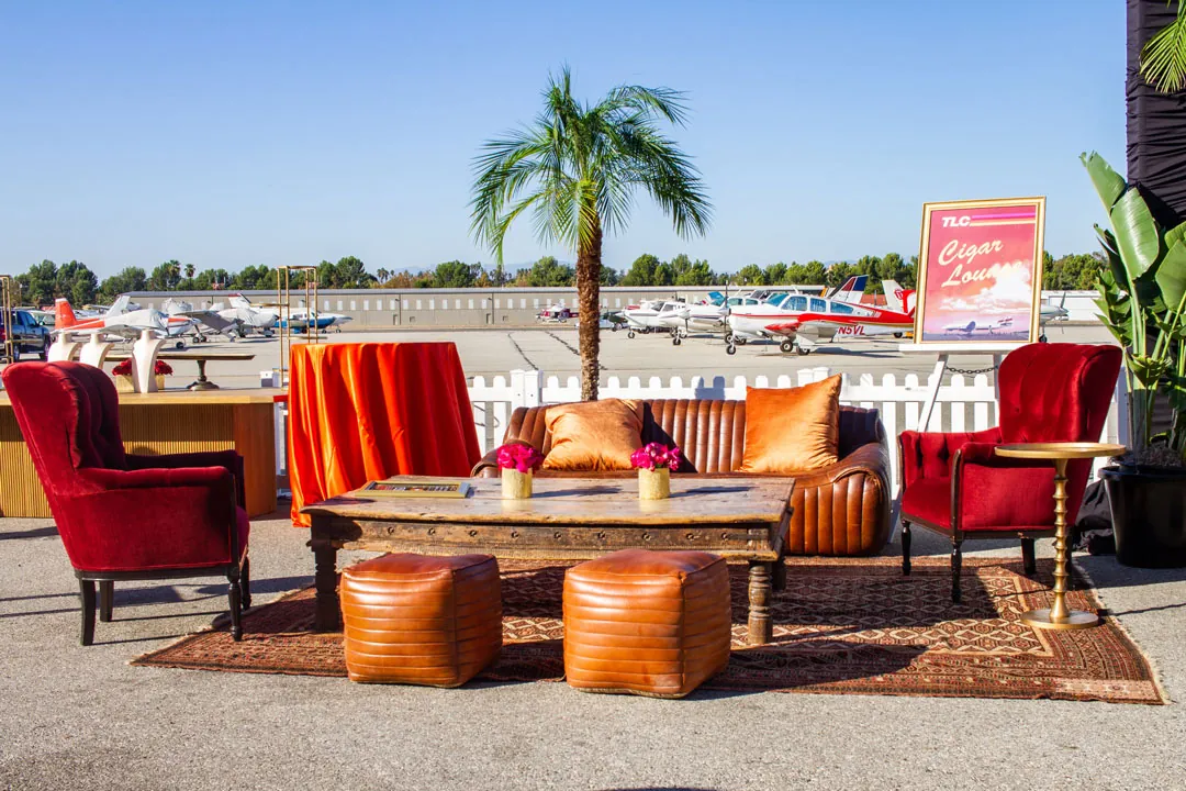 Cigar Lounge with red velvet chairs, tan leather sofa and ottomans set on the runway edge at The Executive Hangar