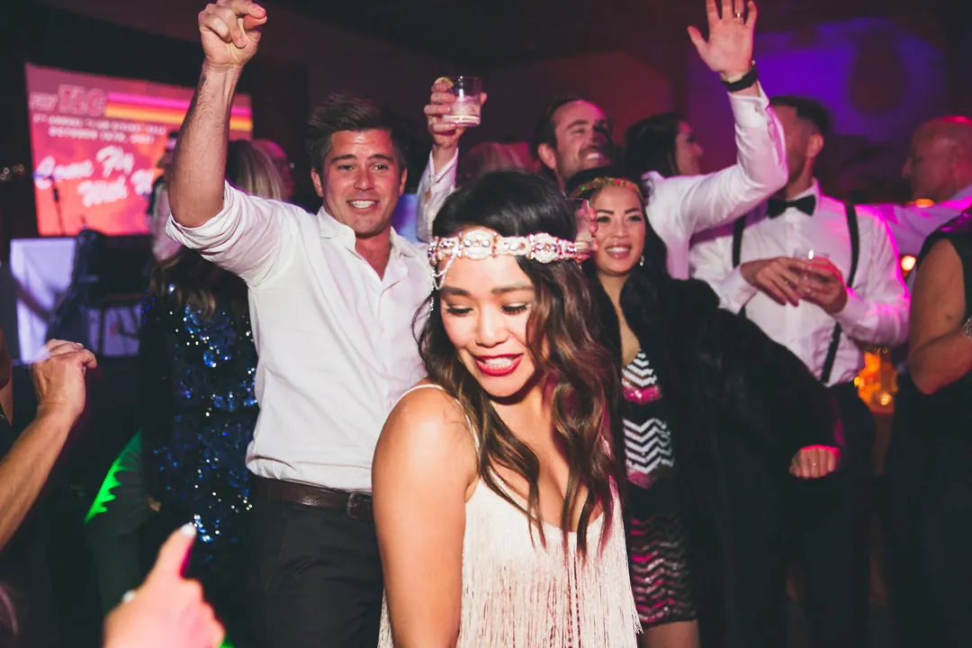 Guests in fringe and sequins dance with drinks raised at the gala after-party at The Executive Hangar
