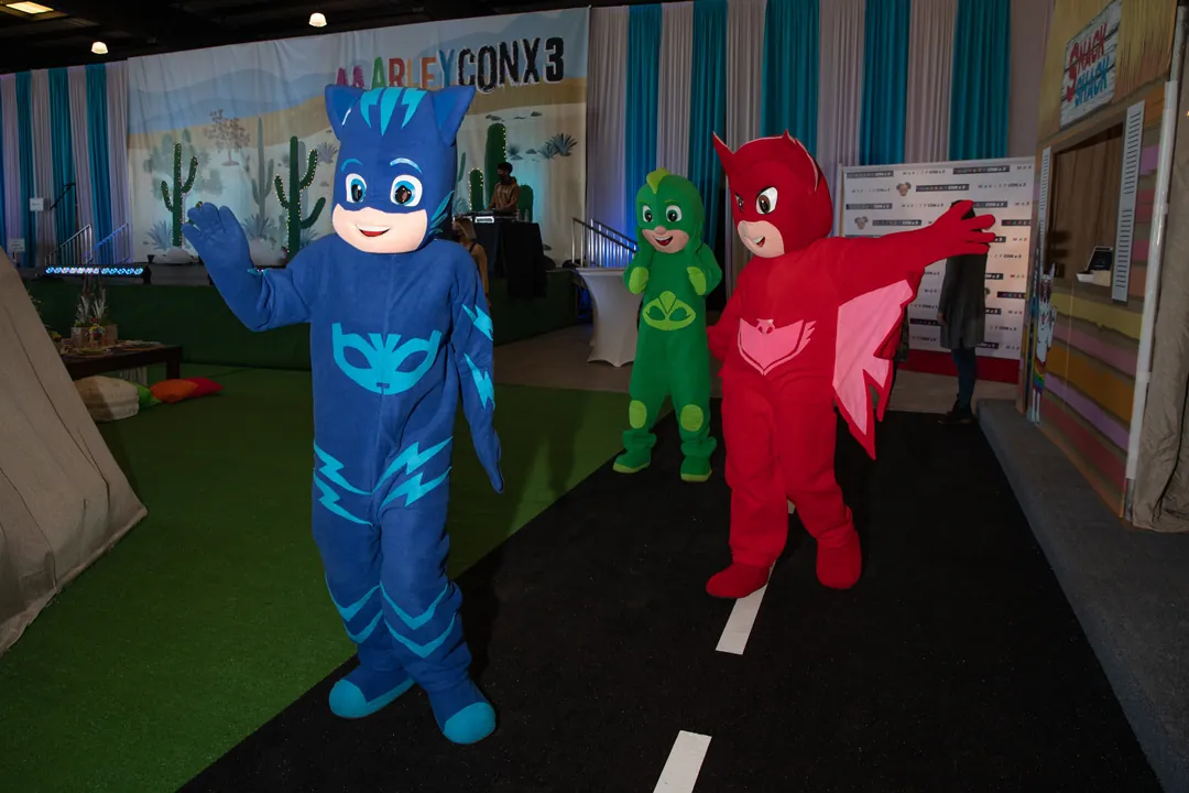Costumed PJ Masks characters greeting guests on the turf floor in front of the MarleyCon x 3 stage