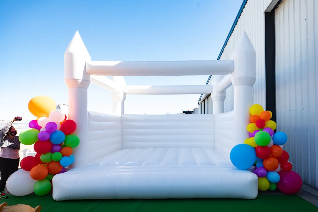 White castle bounce house flanked by rainbow balloon clusters outside The Executive Hangar