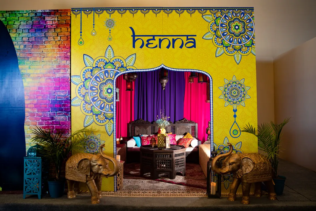 Yellow mandala-patterned henna room entrance with gold elephant statues and jewel-tone curtains at MarleyCon x 3