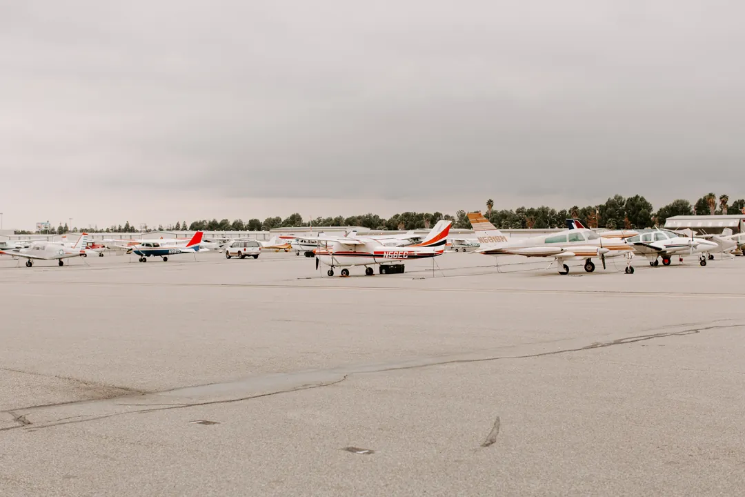 Small private planes parked on the tarmac under overcast skies outside The Executive Hangar in Fullerton