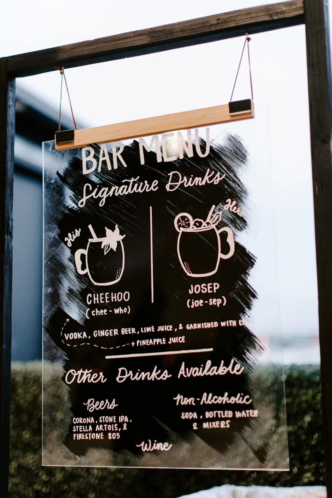 Hand-lettered acrylic bar menu listing the couple's signature Cheehoo and Josep cocktails