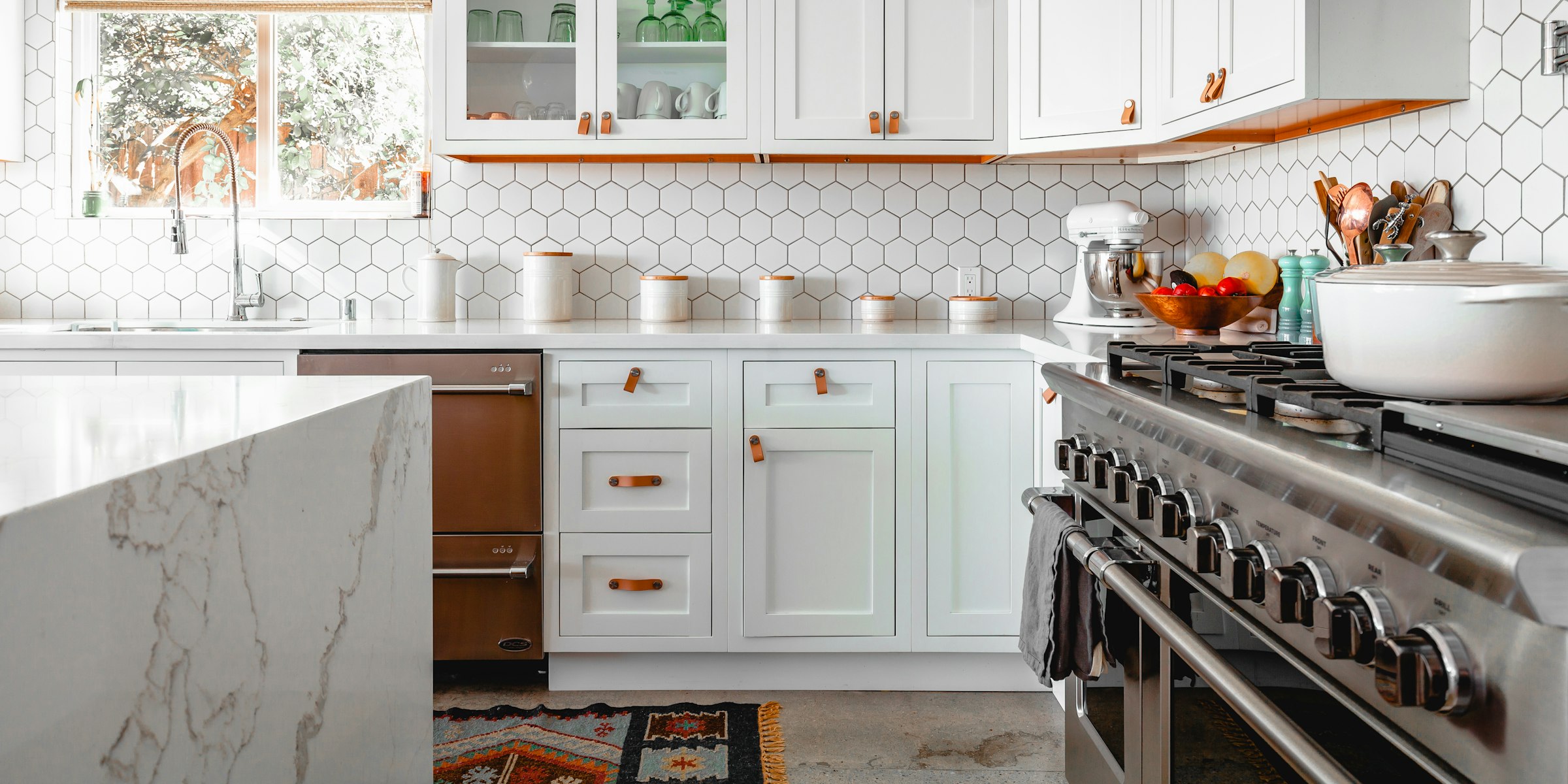 Remodeled kitchen with white cabinets, hexagon tile backsplash and a professional range