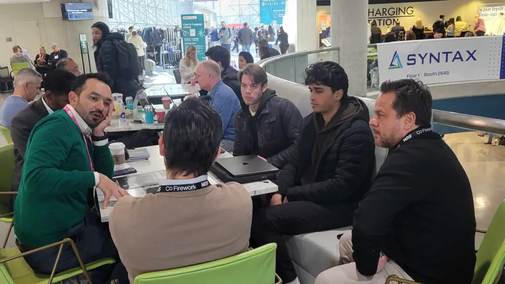 People seated around cafe tables on the Javits concourse in conversation