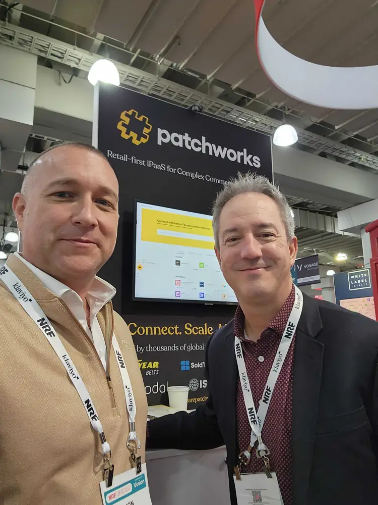 Two people taking a selfie in front of the Patchworks booth
