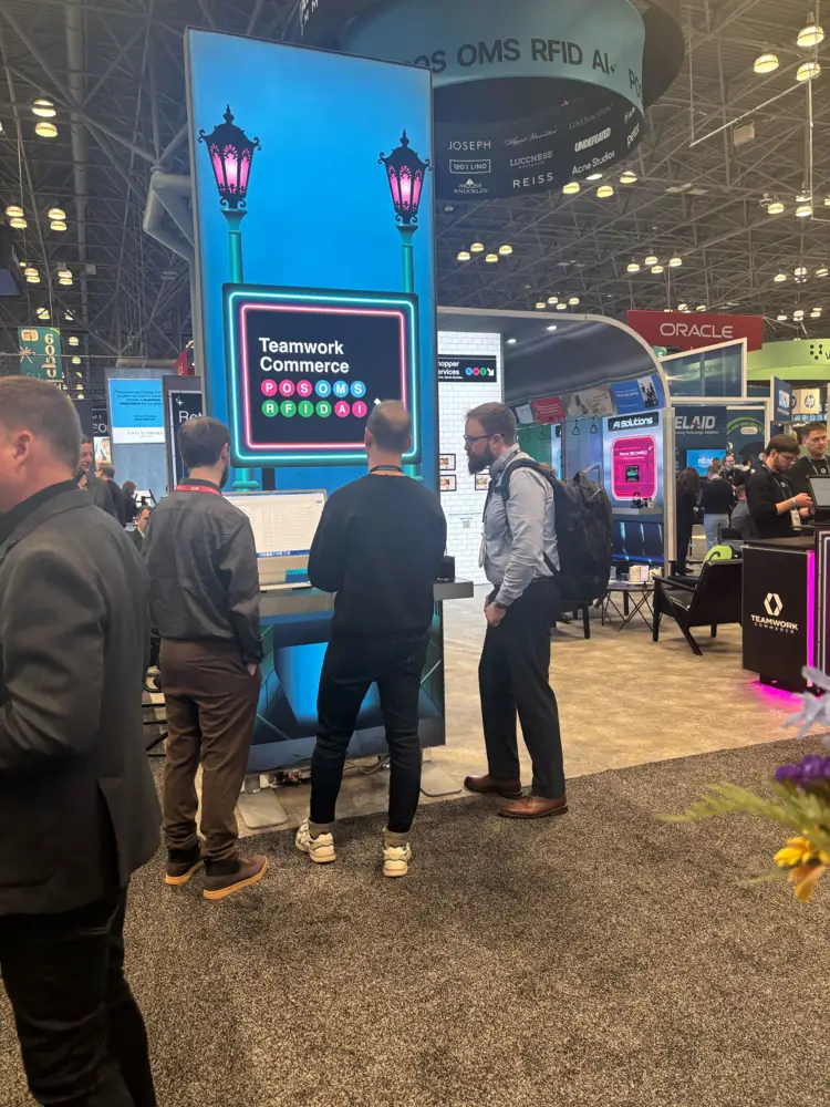 Attendees at the Teamwork Commerce booth looking at a screen listing POS, OMS, RFID and AI