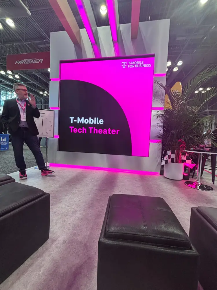 The T-Mobile Tech Theater stage with a speaker standing beside the screen