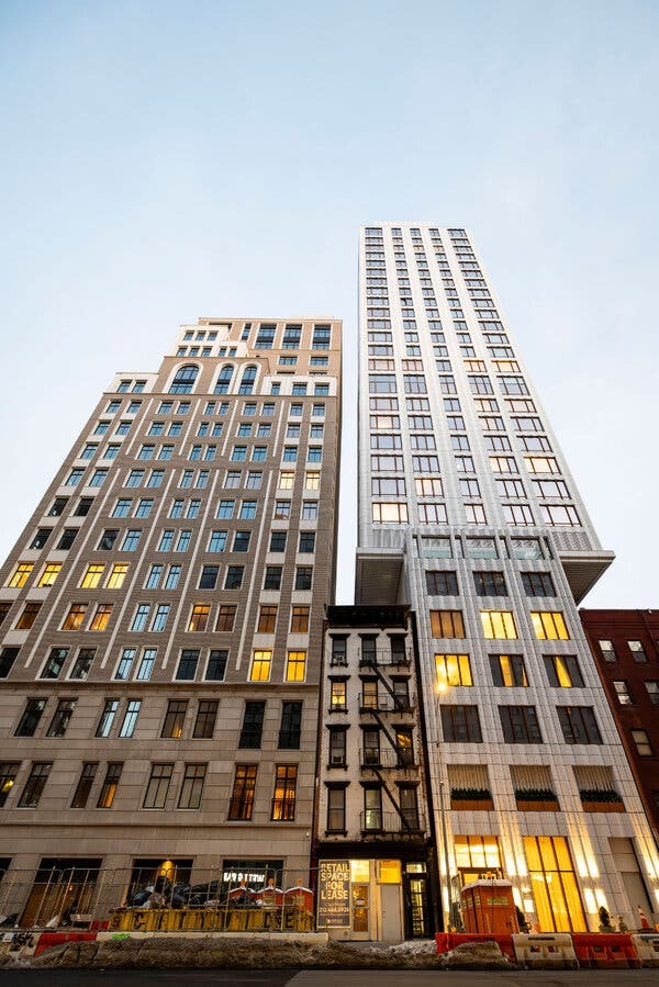 A street-level view of a smaller building between two larger buildings.