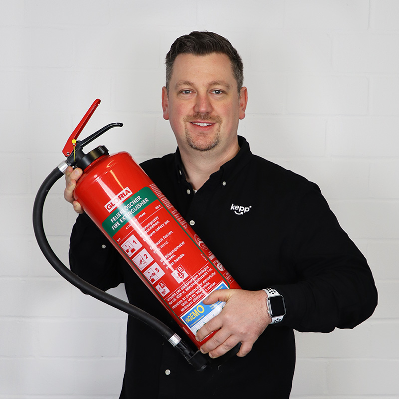 Porträt von Patrick Schulte mit einem Feuerlöscher in der Hand
