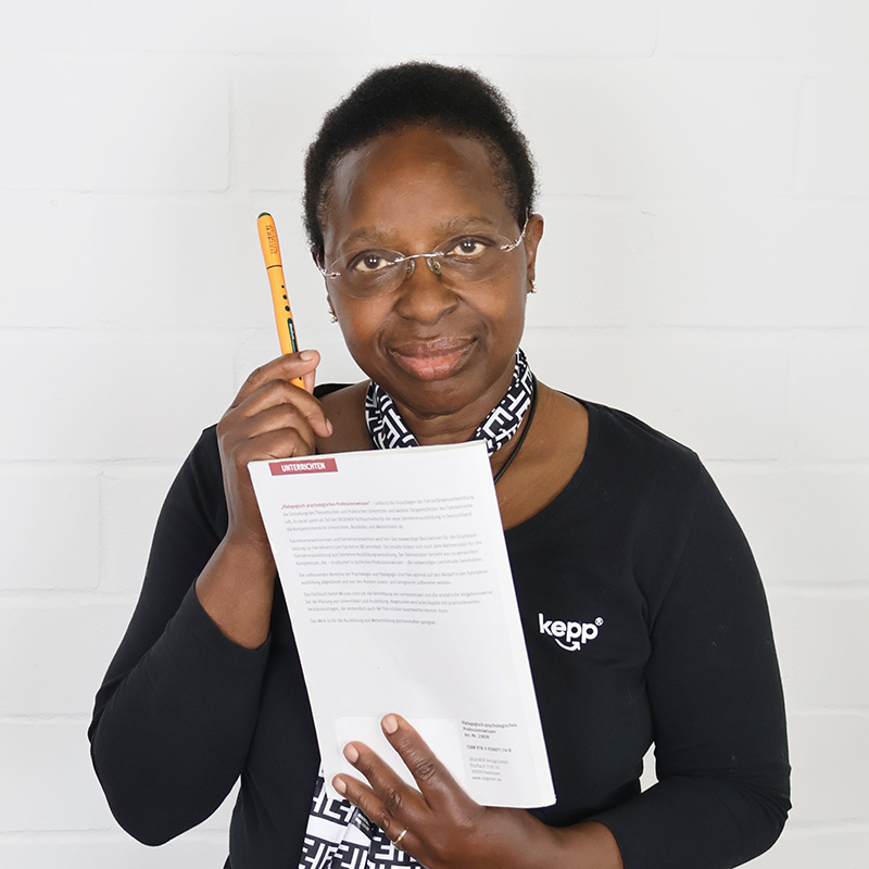 Porträt von Winnie Schulte-Kellinghaus auf dem sie einen Stift und ein Lehrbuch in der Hand hält