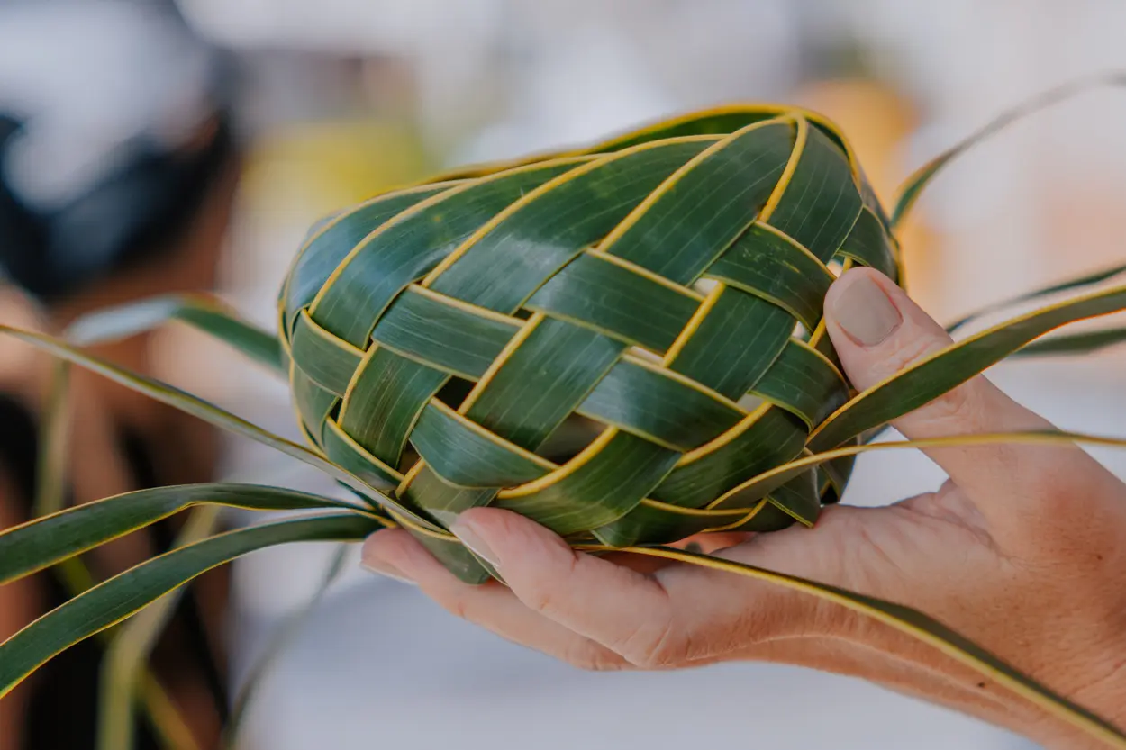 Handcrafted palm leaf basket being held, demonstrating traditional Hawaiian weaving techniques.