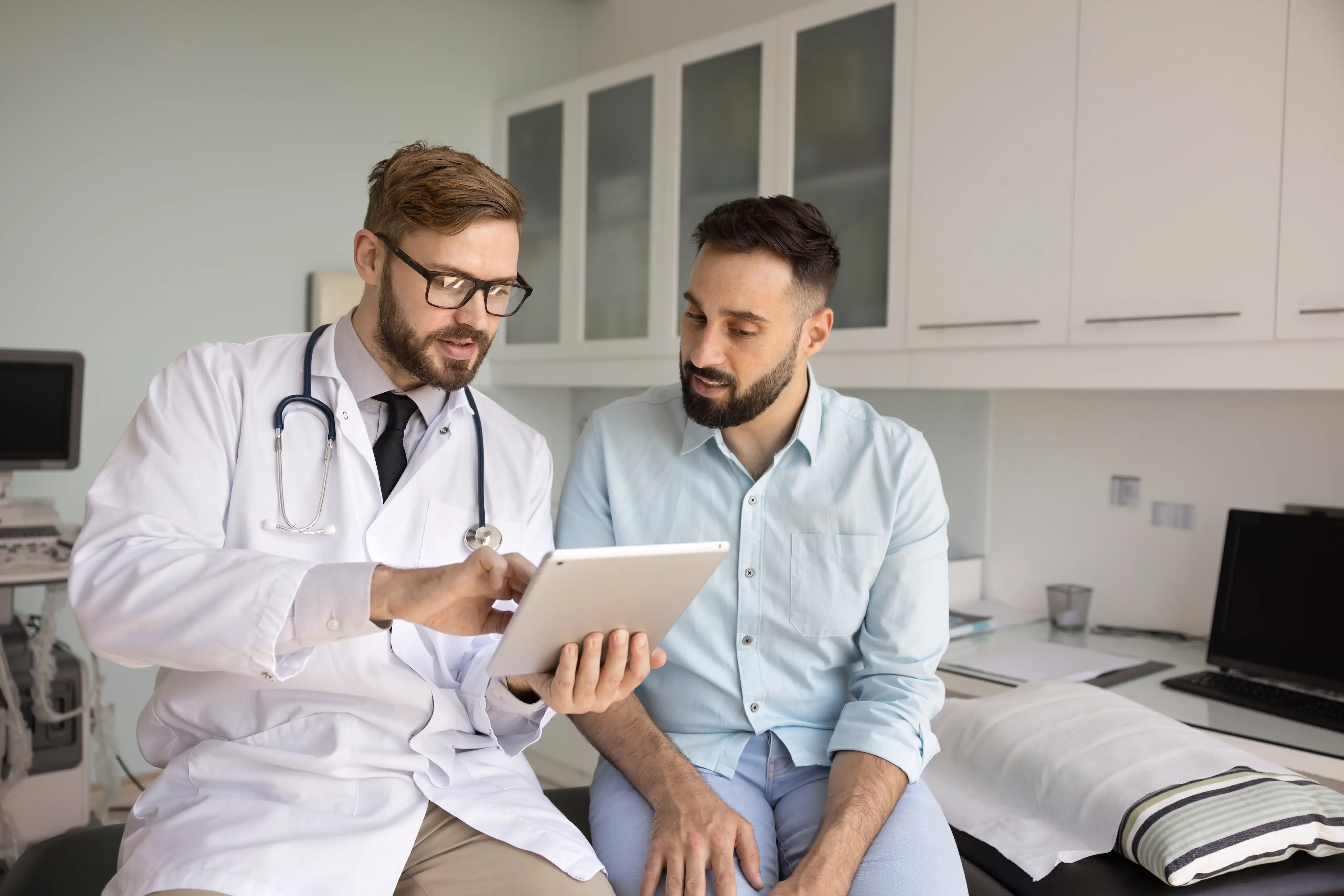 Orthopedic surgeon reviews outcomes data and expectations on Force Therapeutics tablet app with patient in clinic