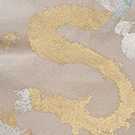 Close-up of textured letter S made with gold leaf on a beige surface.