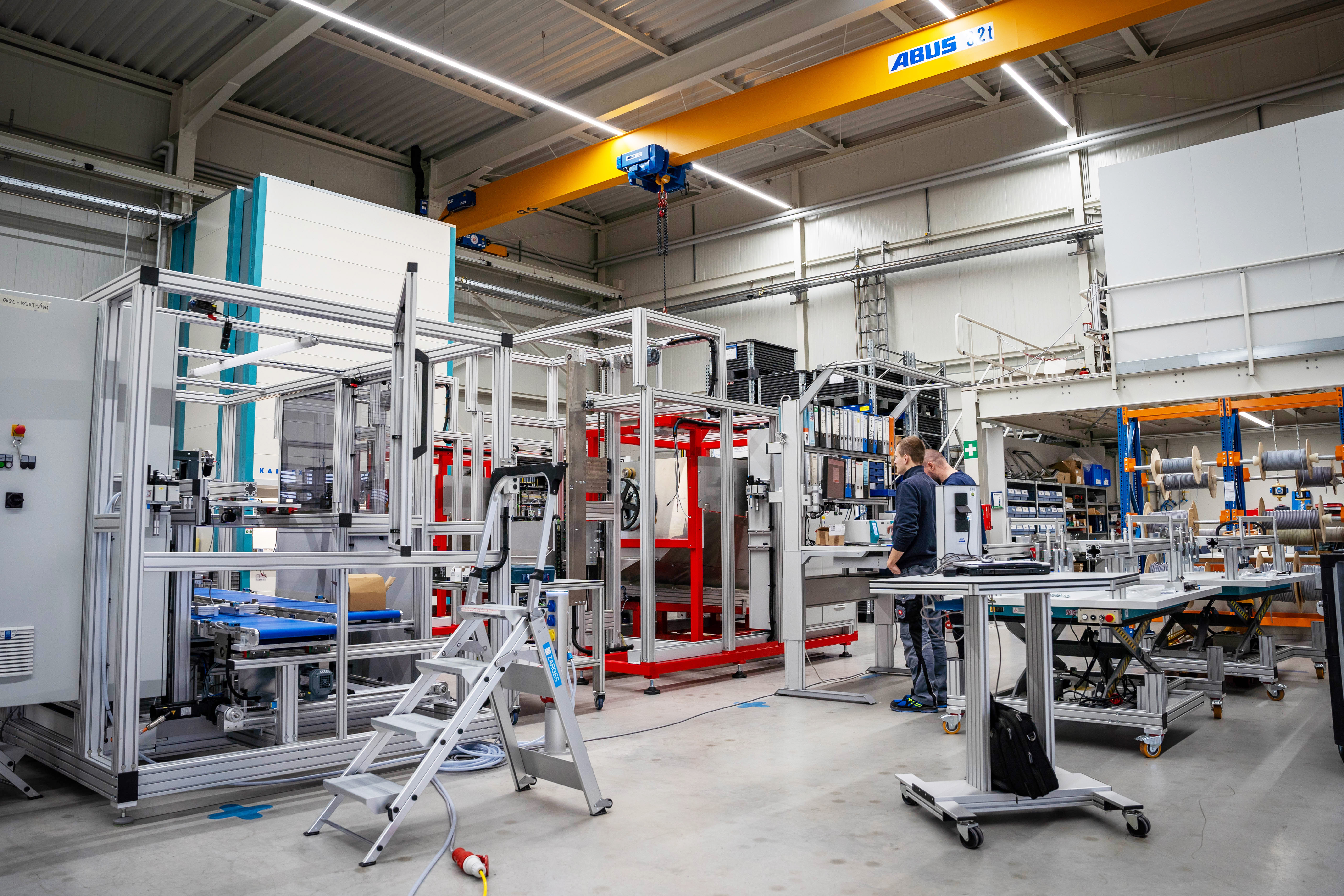 Ein Mann steht in einer Fabrik mit einer Metallmaschine.
