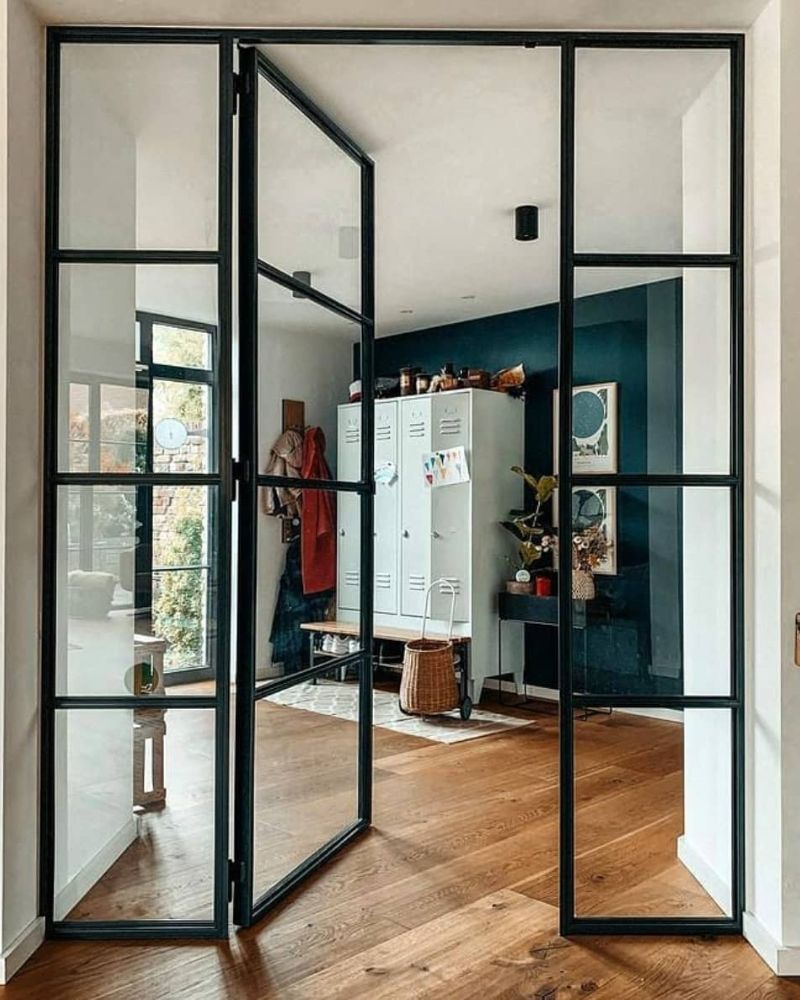 Lofttüren mit schwarzem Stahlrahmen und Glas trennen stilvoll Flur und Wohnbereich