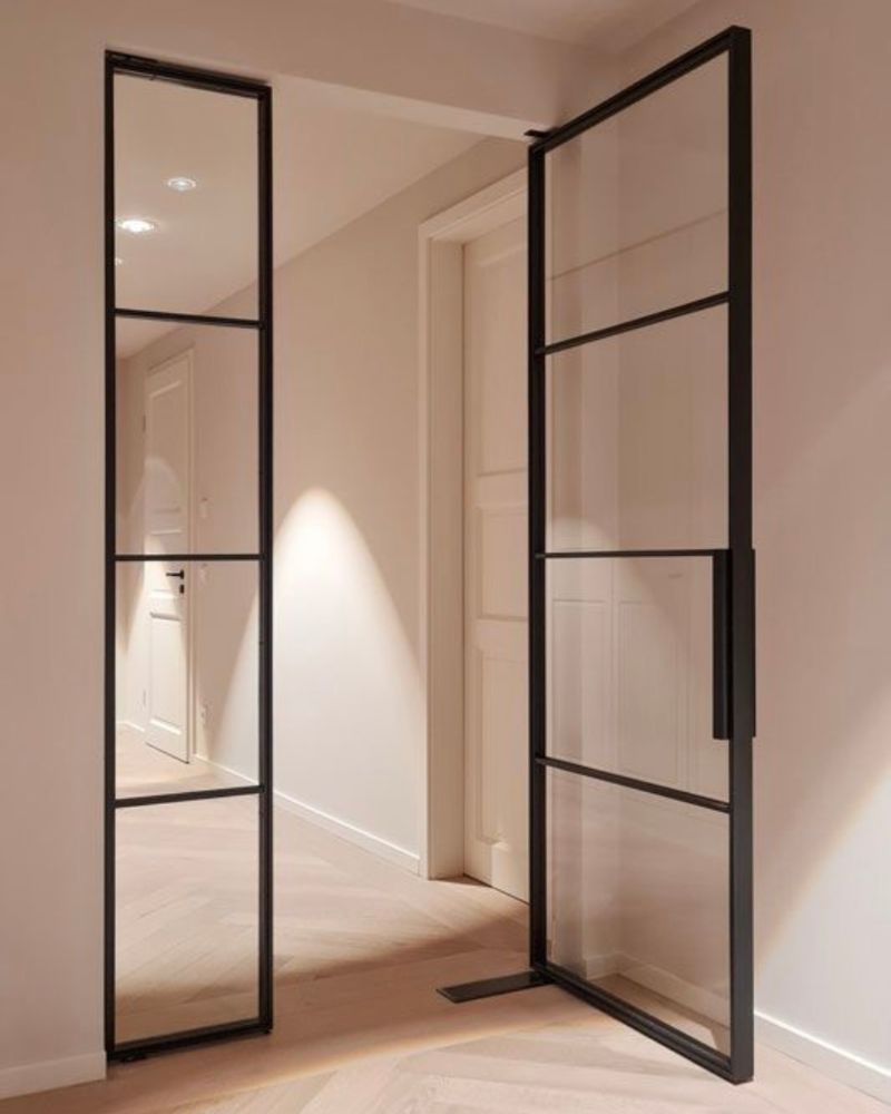 Moderne Glastür mit schwarzem Stahlrahmen und hochwertigen Türbeschlägen