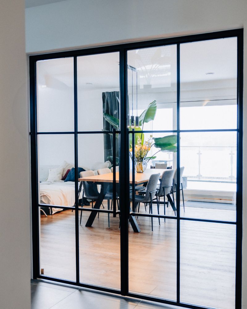 Moderne Lofttür mit schwarzem Stahlrahmen und Glas trennt Wohn- und Essbereich