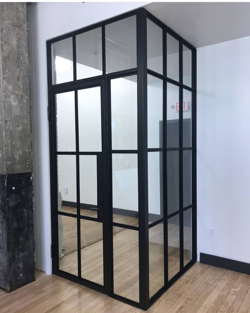 Moderne Glastrennwand mit schwarzem Stahlrahmen und Tür