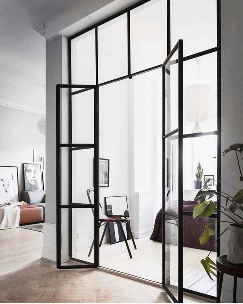 Lofttüren mit schwarzem Stahlrahmen und Glas schaffen eine elegante Verbindung zwischen Wohn- und Schlafbereich im modernen Interior.