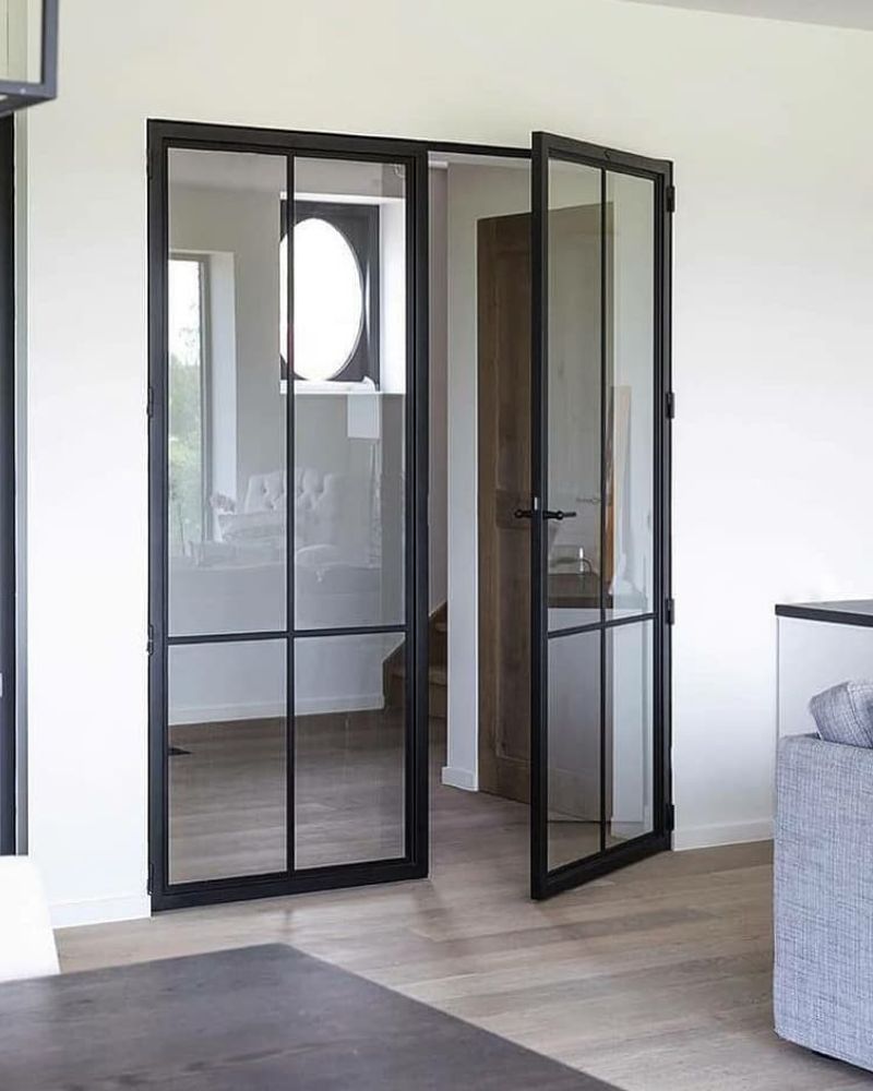 Moderne schwarze Lofttür aus Glas in hellem Wohnraum