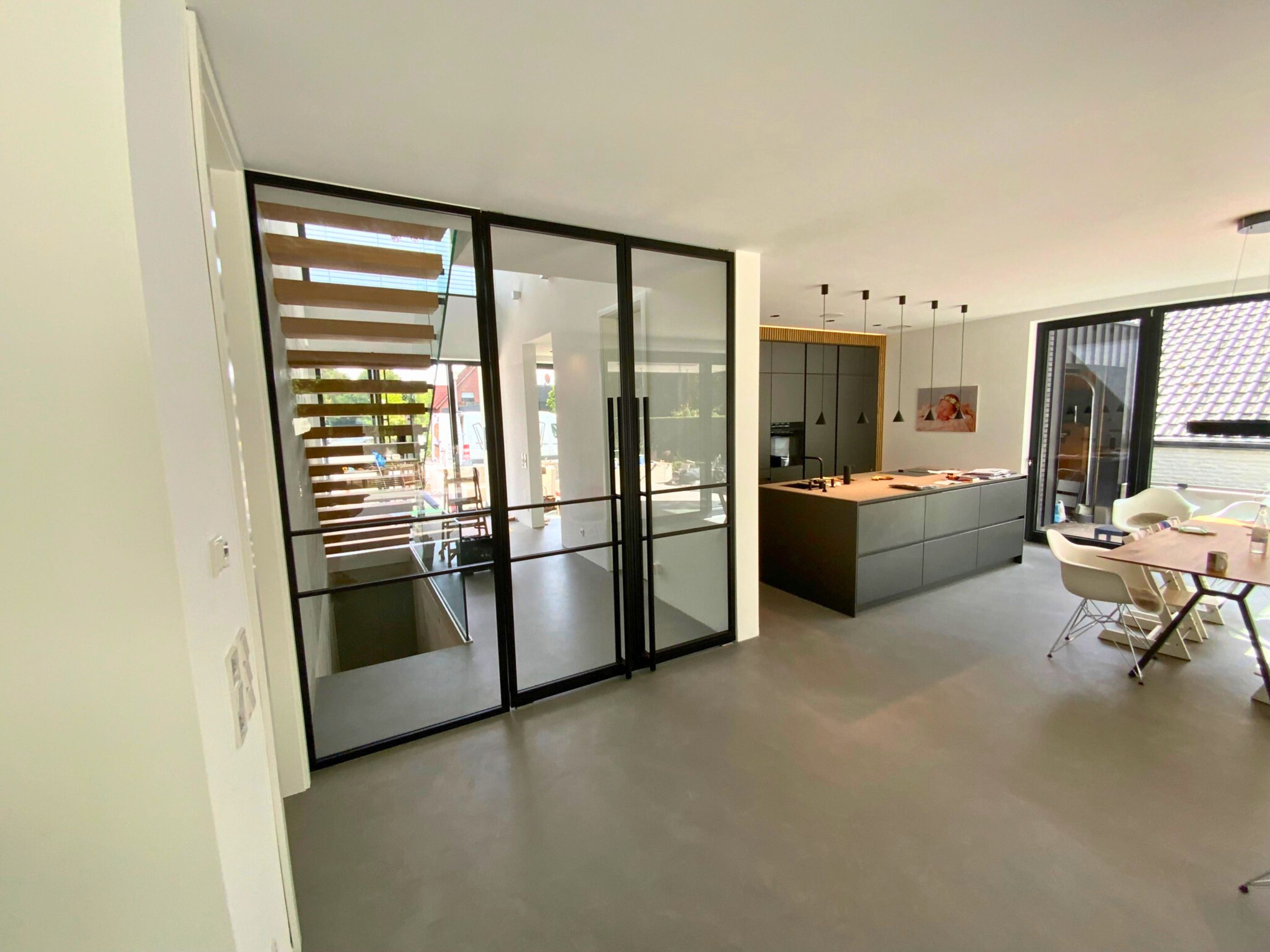 Lofttüren mit schwarzem Stahlrahmen und Glas trennen stilvoll Flur und Wohnbereich