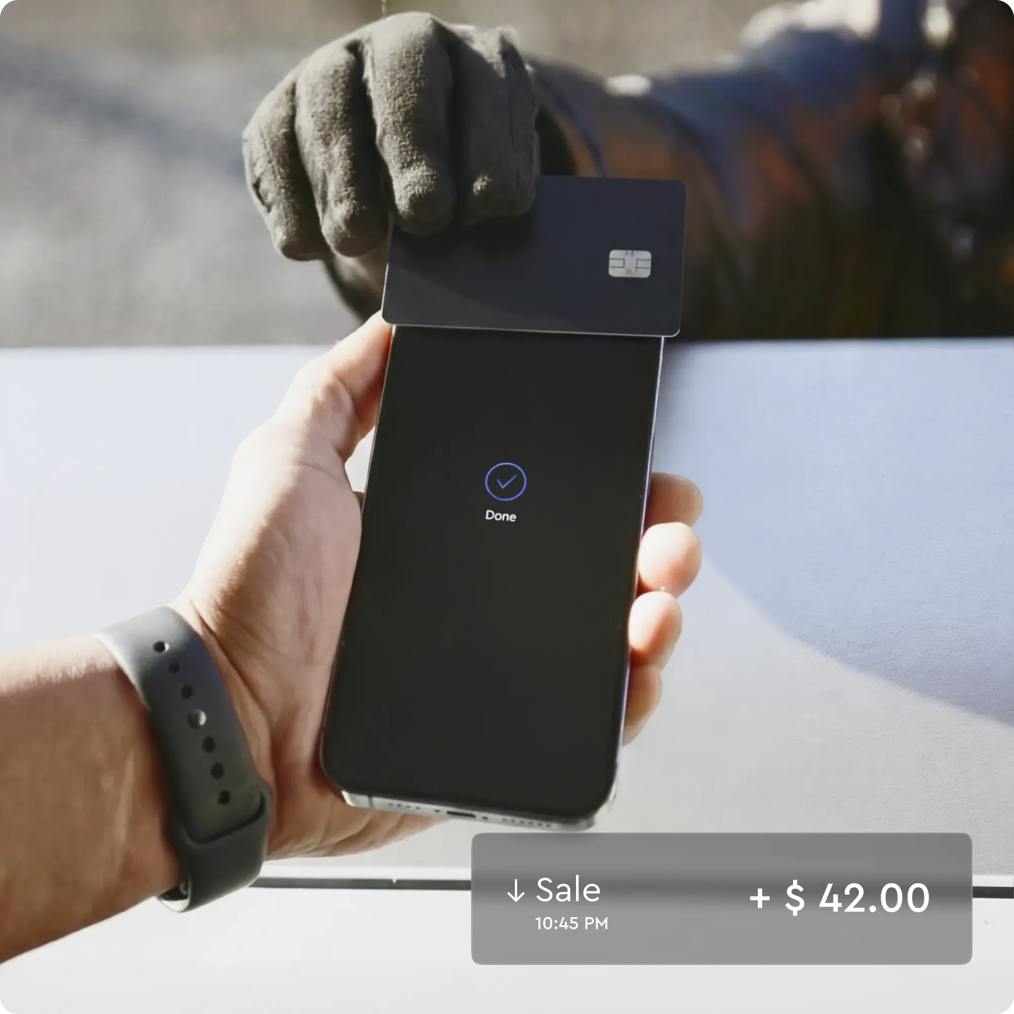 Close-up of a completed Tap to Pay transaction showing a 'Done' confirmation on the phone screen while a customer taps their credit card, with a sale notification of +$42.00.