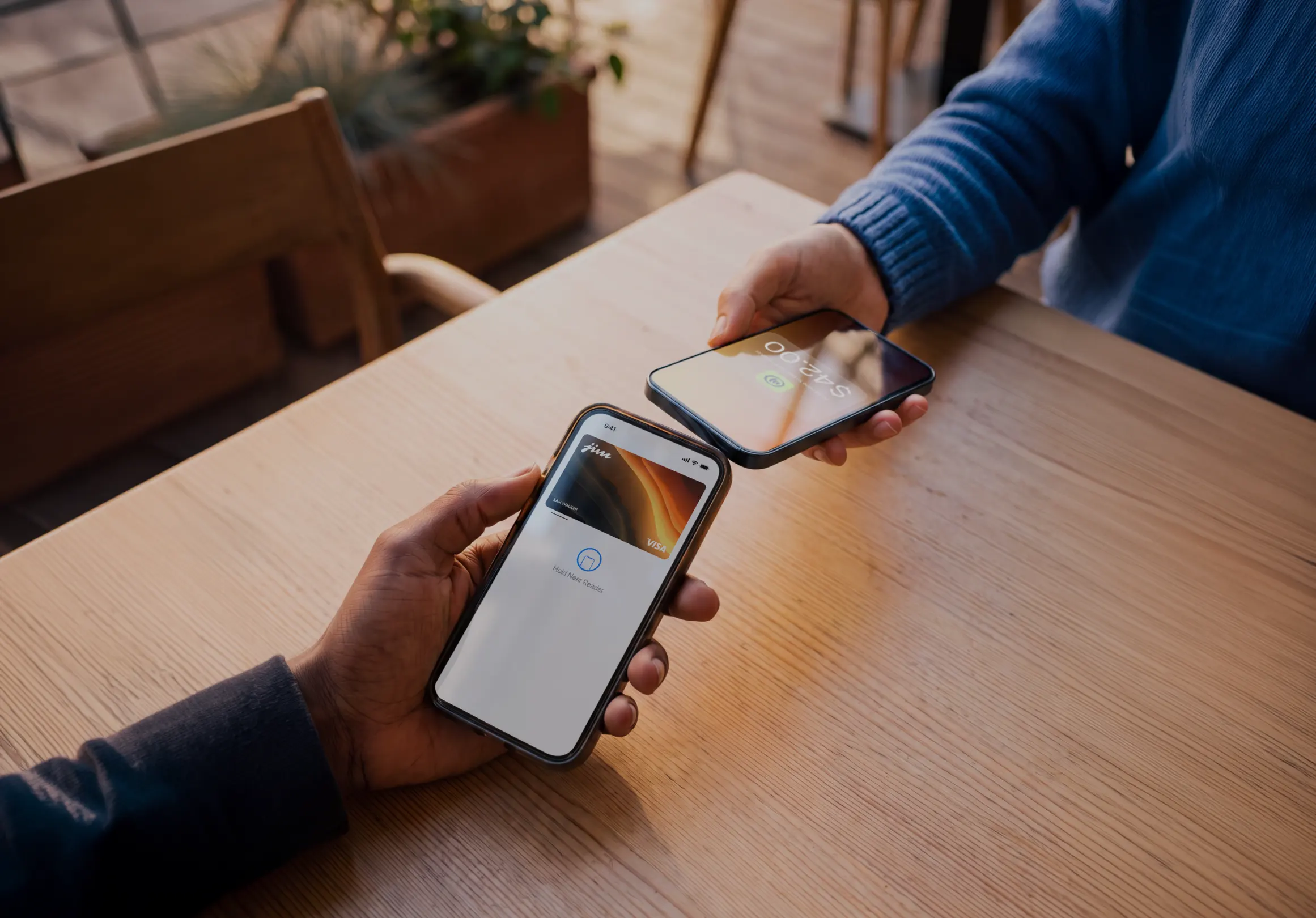 Two phones completing $42.00 Jim tap-to-pay transaction at cafe table