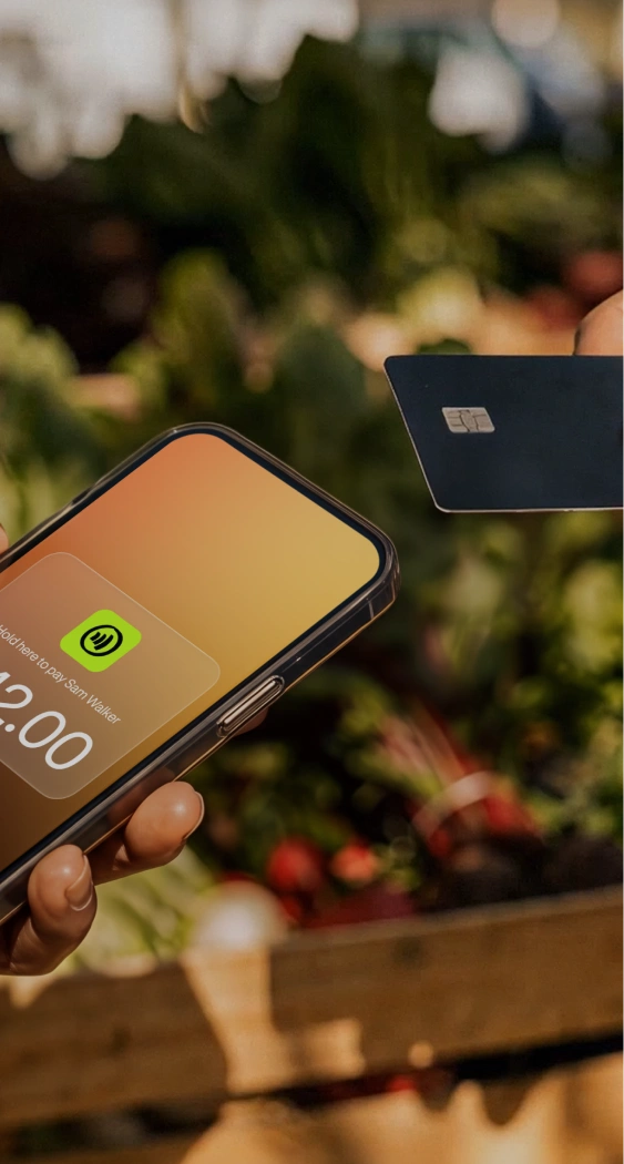 Merchant accepting a card tap on a phone for $42.00 at a farmers market