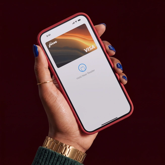 Hand holding smartphone with mobile wallet showing a Visa card and 'Hold Near Reader' prompt.