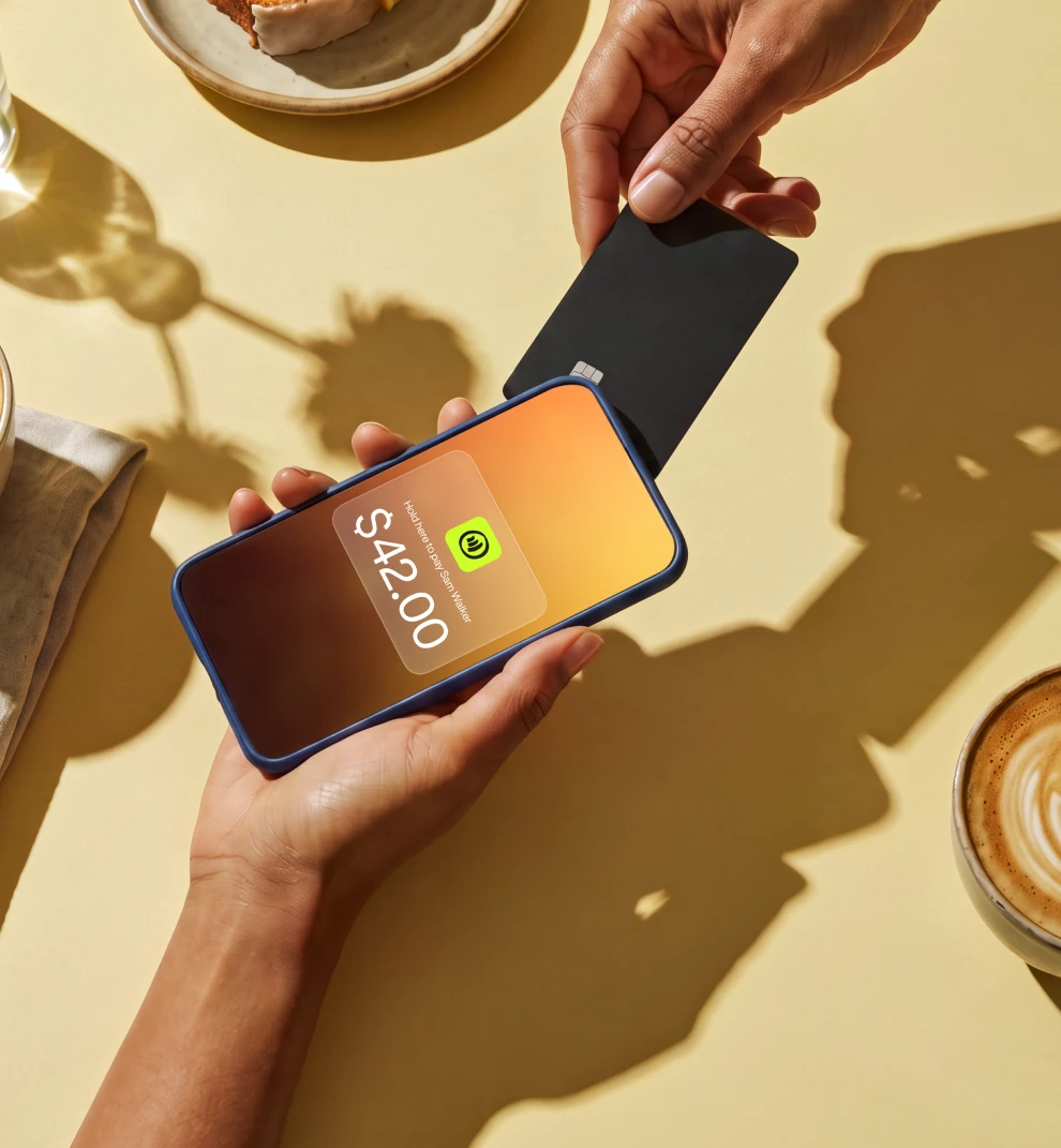 Customer tapping card on phone for $42.00 Jim payment at cafe table