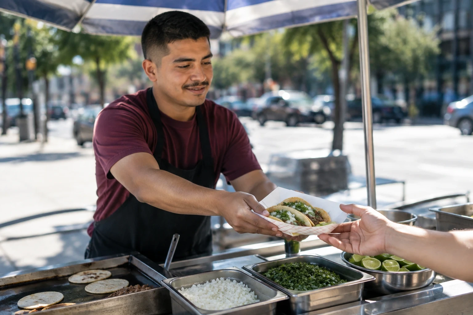 Young street food vendor handing tacos to a customer from his sidewalk food cart