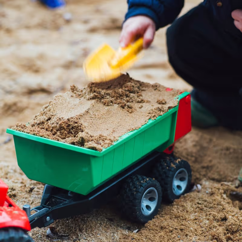 A boy playing with toys in the sand
