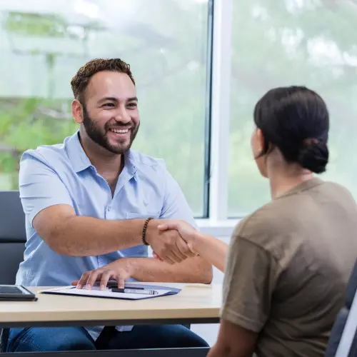 Business representative and client shaking hands during an office consultation.