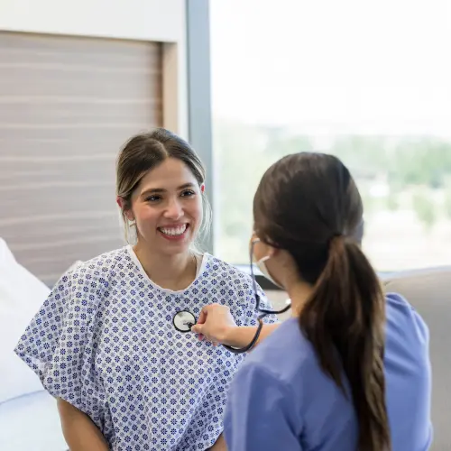 Healthcare provider using a stethoscope to check a patient's vital signs.