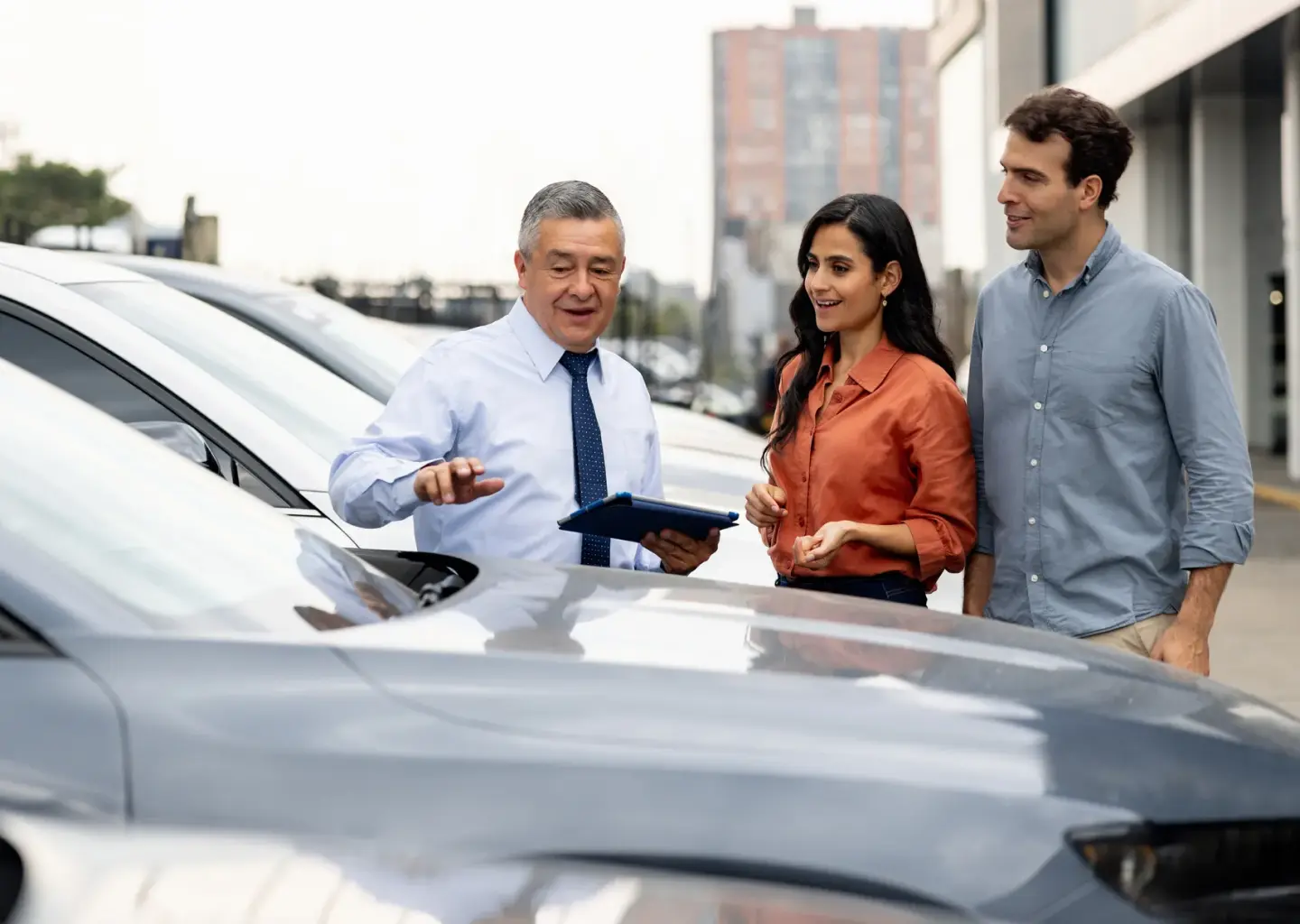 Auto sales representative assisting a couple as they shop for a vehicle at a dealership.
