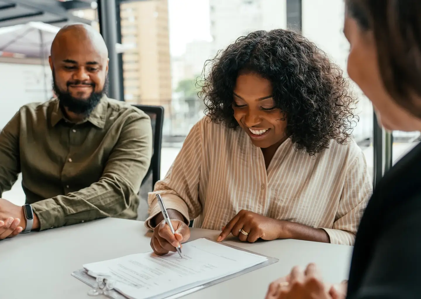 Client signing documents during a meeting with financial or trust advisors.