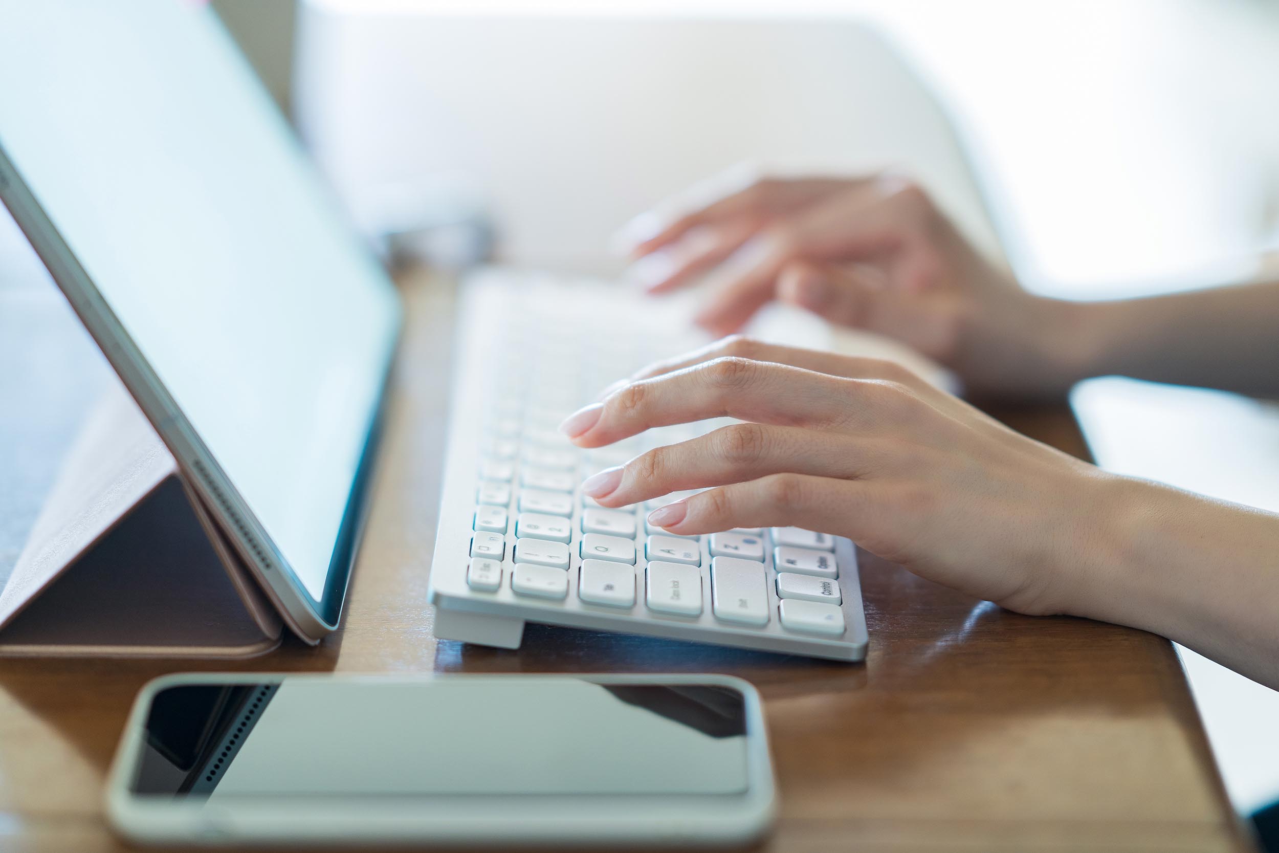 Des mains positionnées au-dessus d'un clavier saisissent du texte à l'ordinateur