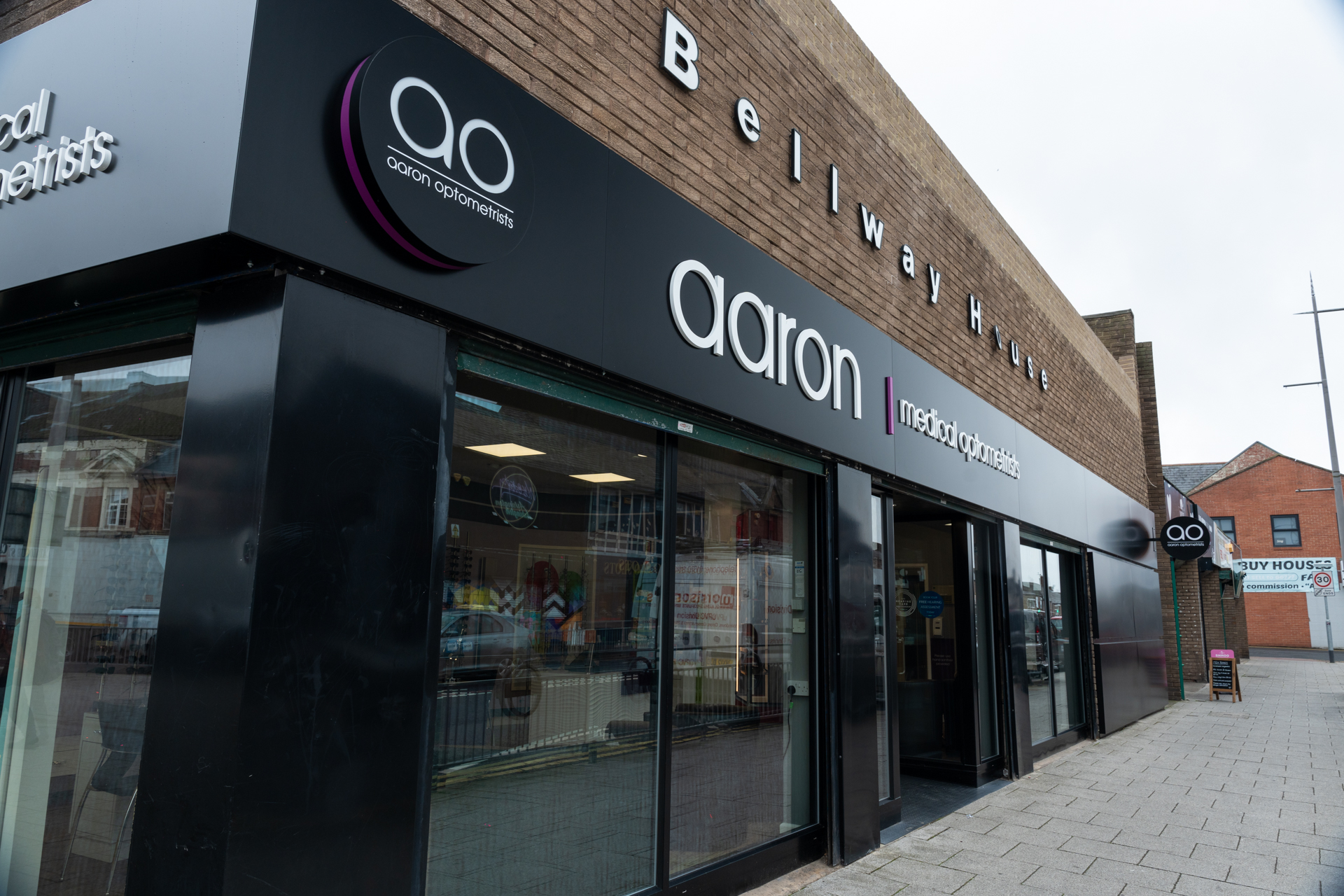 Aaron Optometrists storefront with black signage on Beilway House