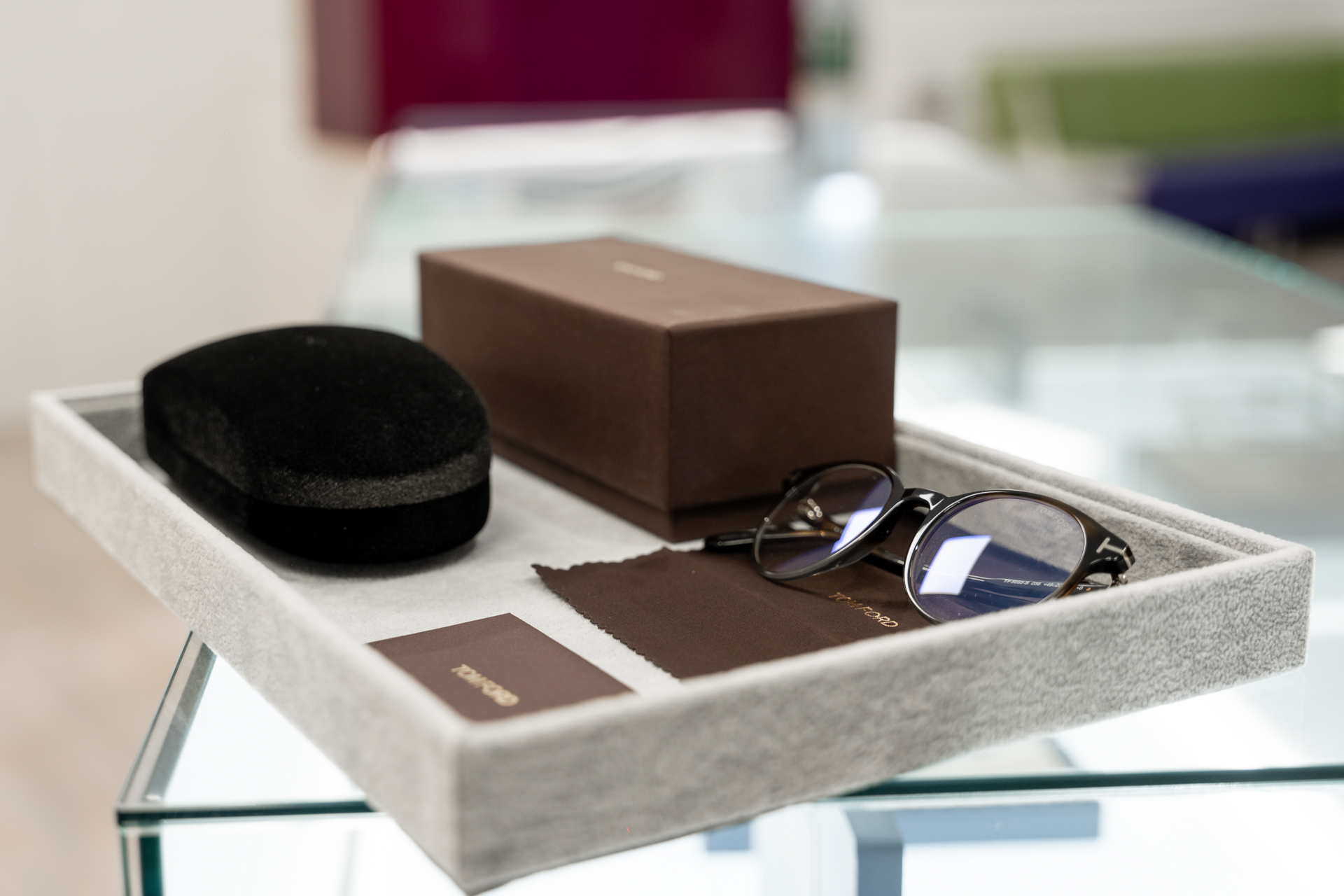 Luxury eyeglasses with brown box and cleaning cloth in a gray tray