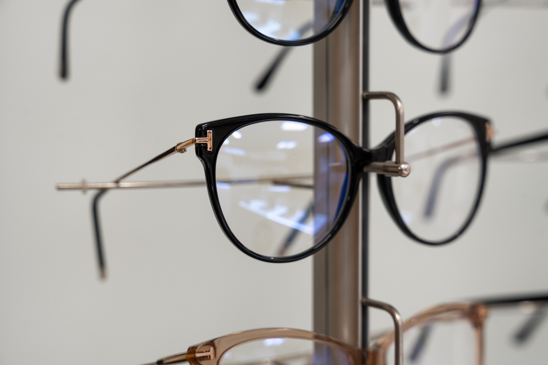 Black and brown eyeglasses hanging on display rack in optical store